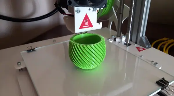 Drukarka 3D drukuje zielony, spiralny wazon.