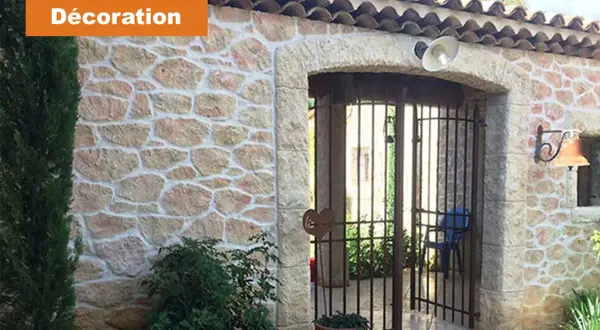 Maison avec un bel enduit pierre apparente, une arche et une grille rouillée.