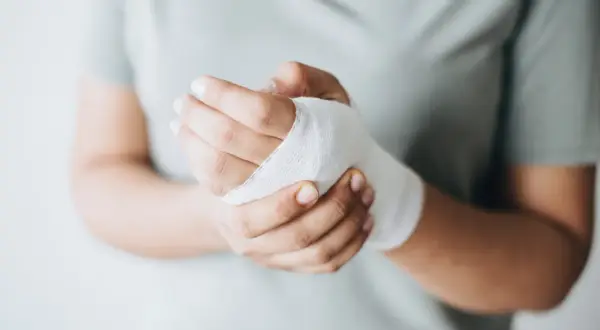Dłoń z bandażem, wspierająca proces gojenia ran. Odpowiednia dieta na gojenie ran przyspieszy powrót do zdrowia.