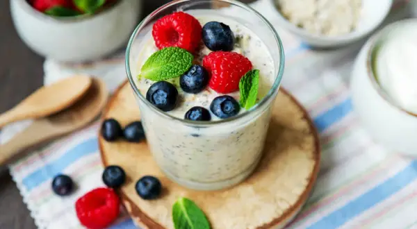 Ein Glas Overnight Oats mit Joghurt, garniert mit frischen Beeren und Minze. Perfekt für ein gesundes Frühstück.
