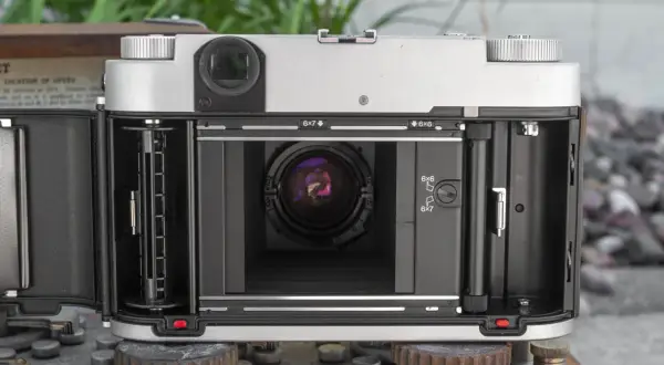 The open back of a Fuji GF670W medium format camera, revealing the film path and lens.
