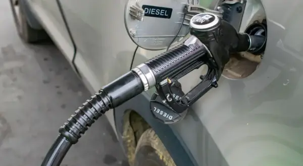 Tankowanie diesla. Zbliżenie na pistolet paliwowy wlewu paliwa samochodu. Informacja o rodzaju paliwa "DIESEL" jest widoczna.