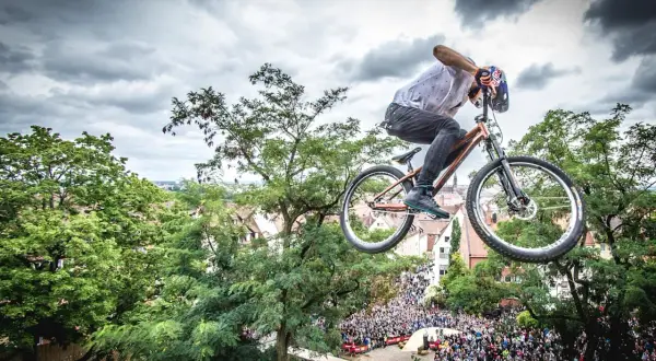 Kolarz w powietrzu na rowerze, idealnym na pumptrack, nad tłumem widzów.
