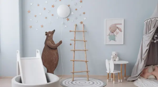 Douce couleur peinture chambre bébé bleu ciel, décorée d'étoiles et d'un ours. Un coin jeu avec toboggan et tapis.