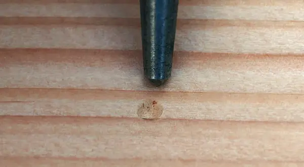 Ein Metallstift markiert eine Stelle auf Holz, bereit zum schamottstein bohren.