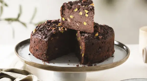 Torta di pane al cioccolato, ricca e golosa, con pistacchi e cacao, servita su un'alzata.