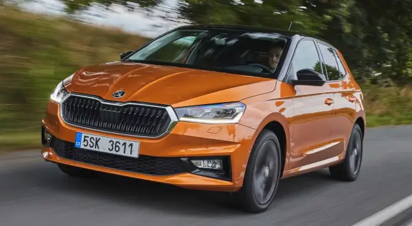 En orange Skoda Fabia kör på en väg. Inga problem med denna bil, bara en härlig tur.