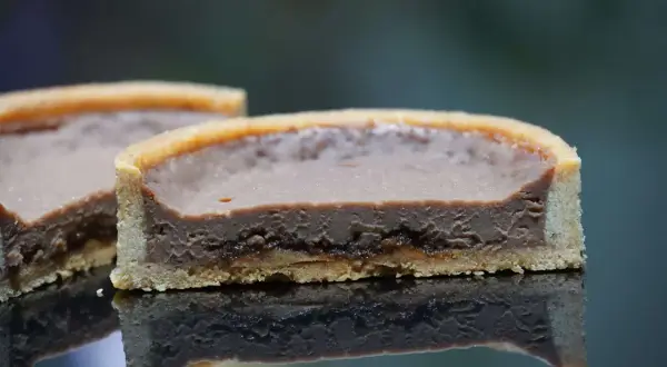 Tarte chocolat praliné croustillant, une tranche révèle sa texture onctueuse et sa base dorée.