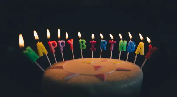 Płonące świeczki z literami tworzą napis "Happy Birthday". Idealne życzenia urodzinowe po angielsku na torcie.