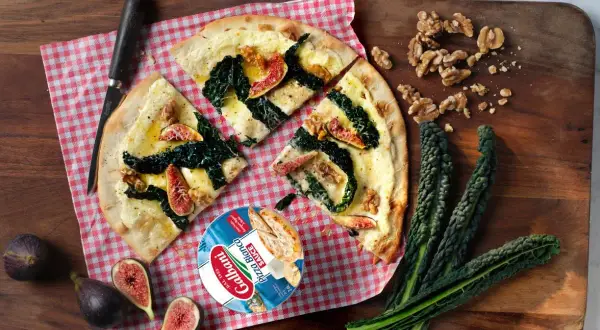 En läcker pizza sverige med fikon, grönkål och valnötter. Serveras på en träskärbräda med färska ingredienser.