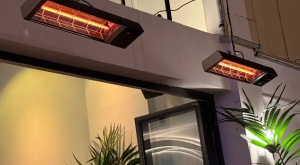 Dwa wiszące promienniki ciepła elektryczne emitują przyjemne, pomarańczowe światło, ogrzewając przestrzeń.