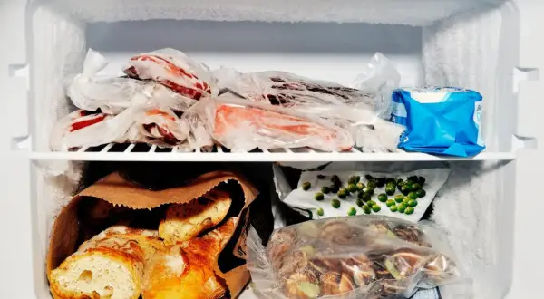 Zamrożone mięso, pieczywo, groszek i inne produkty spożywcze w zamrażarce.