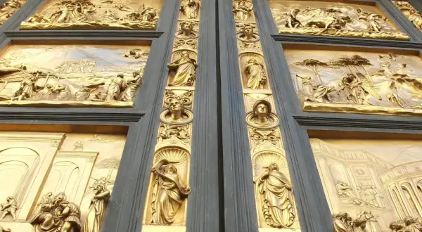 Detalle de las puertas del paraíso, con relieves dorados que narran escenas bíblicas y figuras alegóricas.