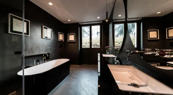 Elegantes, dunkles Badezimmer mit freistehender schwarzer Wanne, Doppelwaschbecken und moderner Spiegelarchitektur.