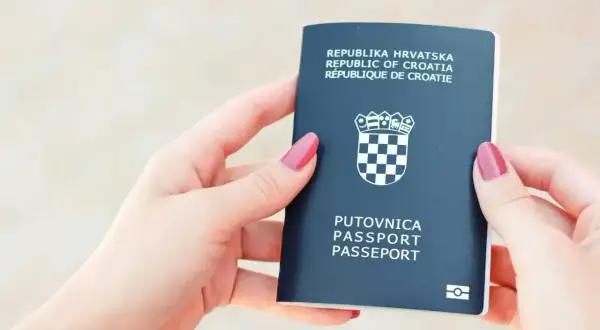 Dwie dłonie trzymają ciemnogranatowy paszport Republiki Chorwacji. Czy do Chorwacji potrzebny jest paszport? Tak, ten dokument jest niezbędny.