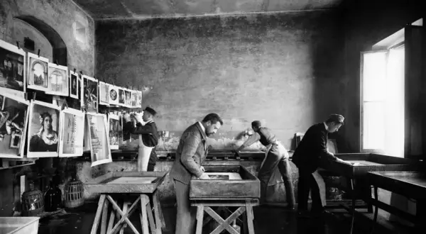 Alessandro Bardi e collaboratori lavorano in un laboratorio di stampa, con stampe appese e vasche per il trattamento.