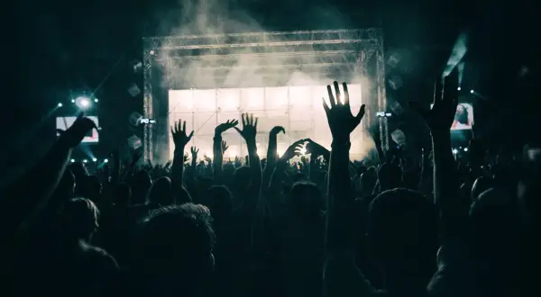 Folla in estasi al ritmo del dj techno berlino, mani alzate verso il palco illuminato.