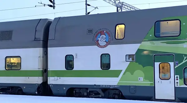 Ein Nachtzug mit Weihnachtsmann-Logo und grüner Landschaftsdekoration im Schnee.