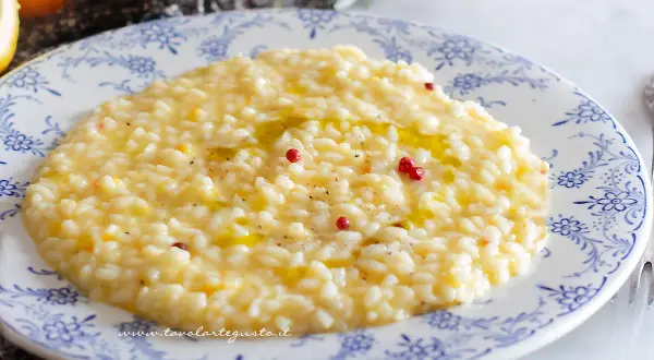 Un cremoso risotto al limone gourmet, guarnito con pepe rosa e un filo d'olio, pronto per essere gustato.