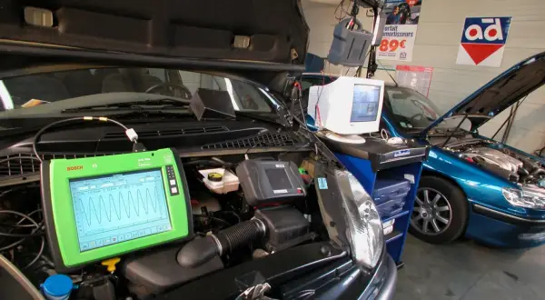 Diagnostic automobile chez Opel France. Un écran Bosch affiche des courbes, une voiture bleue est en réparation.