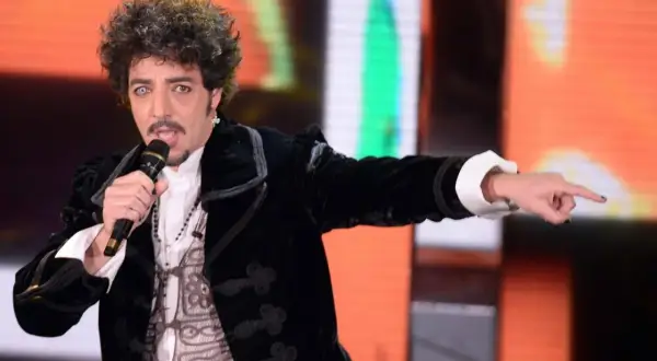 Max Gazzè canta con microfono, vestito elegante, con un'espressione intensa. Sembra che stia raccontando storie con i suoi testi, come se fosse "sotto casa".