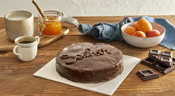 Una deliziosa torta Sacher lucida, con caffè, latte, marmellata di albicocche e cioccolato fondente.