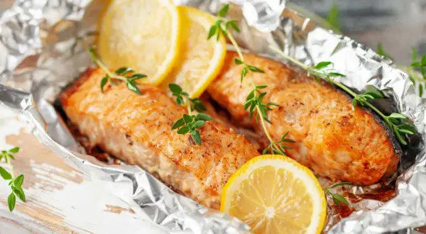 Deux pavés de saumon en papillote, ornés de rondelles de citron et de brins de thym frais, prêts à être dégustés.