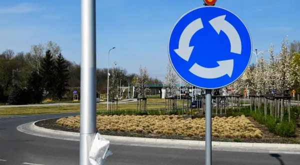 Znak informuje, kto ma pierwszeństwo na rondzie. Trzy białe strzałki na niebieskim tle wskazują kierunek ruchu i sugerują, że pojazdy na rondzie mają pierwszeństwo.