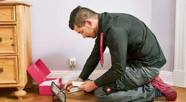 Technik sprawdza instrukcję na tablecie, przygotowując się do instalacji światłowodu. Dowiedz się, ile kosztuje podłączenie światłowodu.