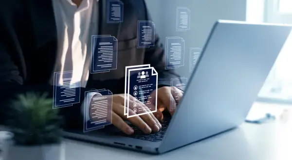 Biznesmen pracuje przy laptopie, przeglądając dokumenty. Wirtualne ikony dokumentów unoszą się wokół, symbolizując zarządzanie danymi. Kto to mocodawca? To ten, kto zleca zadanie.