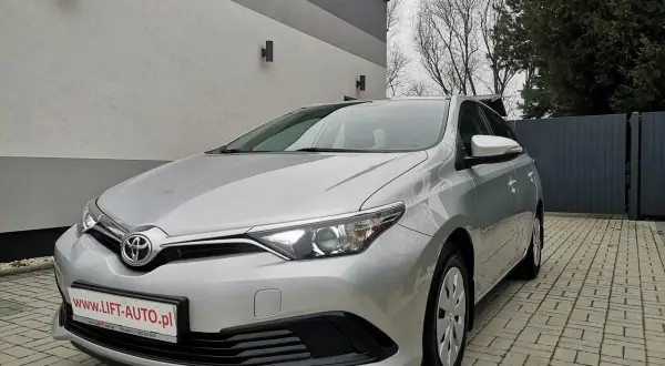 Srebrna Toyota Auris 1.6 benzyna zaparkowana na podjeździe z kostki brukowej.