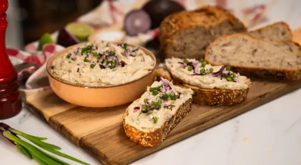 Pyszna pasta z tuńczyka na świeżym chlebie, posypana szczypiorkiem i czerwoną cebulką. Idealna na szybką przekąskę.