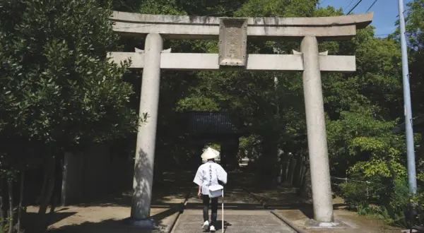Pielgrzym w tradycyjnym stroju przechodzi pod bramą torii na wyspie Shikoku.