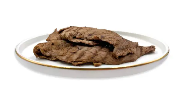 Piatto di paillard di manzo grigliato, sottili fettine di carne con striature scure, servite su un piatto bianco con bordo dorato.