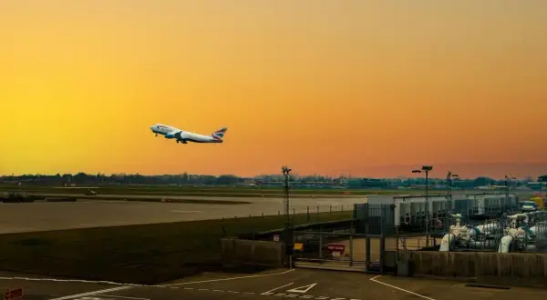 Flugzeug steigt auf vor orangefarbenem Himmel am internationalen Flughafen von London.