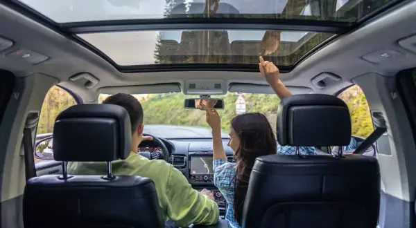 Familie im Auto mit Panoramadach. Die Sonne scheint durch das Fenster, hoffentlich kein Sonnenbrand!
