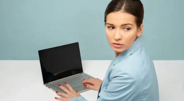 Kobieta z laptopem, nerwowo rozglądająca się na boki. Czy to objawy stalkingu?