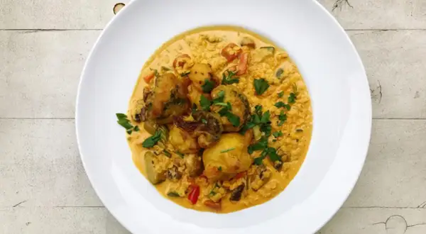 Pyszny ryż z curry z warzywami i kawałkami kurczaka, posypany świeżą natką pietruszki.