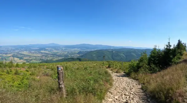 Kamienista ścieżka w polskich górach z widokiem na dolinę i niebieskie niebo.