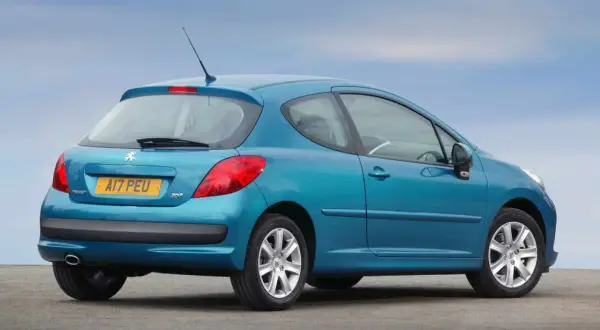 Niebieski Peugeot 207 1.4 HDI z tablicą rejestracyjną AI7 PEU stoi na tle błękitnego nieba.