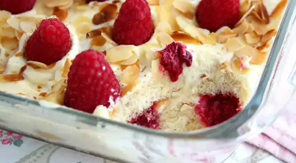 Un délicieux tiramisu framboise, garni de fruits rouges frais et d'amandes effilées, prêt à être dégusté.