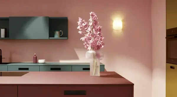 Elegante cocina rosa con encimeras de color burdeos, armarios verde azulado y un ramo de flores rosas.