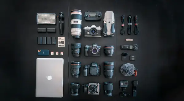 A filmmaker's dream setup, showcasing a serious case of gear acquisition syndrome: cameras, lenses, drone, laptop, and audio gear laid out.