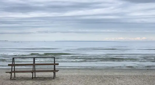 Pusta ławka na plaży w Jelitkowie zaprasza do podziwiania fal. To idealne miejsce na relaks i odkrywanie uroków tego nadmorskiego kurortu.