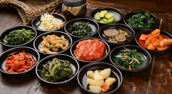 Bogactwo koreańskich **banchan**: kimchi, marynowane warzywa, sałatki z ziół i wiele innych, podane w małych miseczkach.