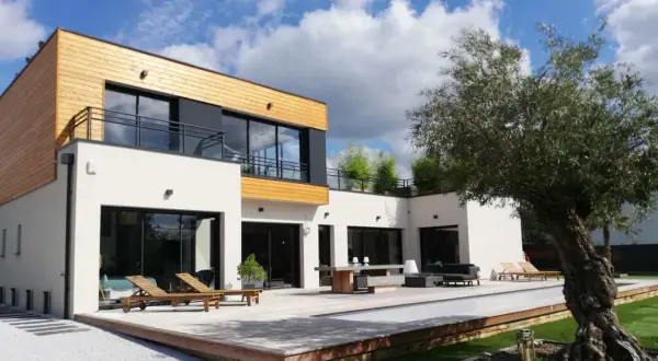 Maison moderne avec piscine et terrasse en bois. On se demande combien de m3 d'eau pour construire une maison comme celle-ci.