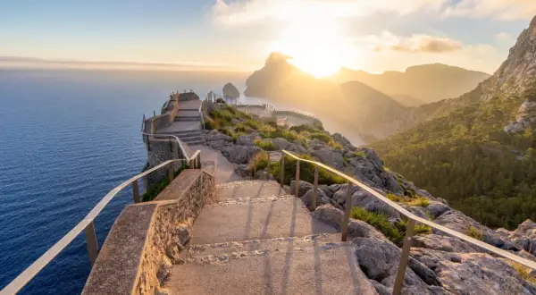 Sonnenuntergang über dem Meer, ein Pfad mit Treppen führt zu Aussichtspunkten. Perfekte Reiseziele im Februar für atemberaubende Ausblicke.