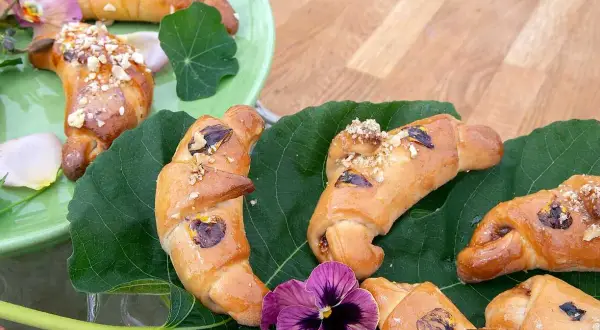 Gyllene gifflar med nötter och torkad frukt, vackert arrangerade på gröna blad. Ett härligt recept på hembakade gifflar!