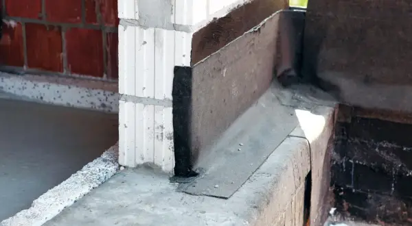 Papa na fundament chroni przed wilgocią, widoczna na narożniku budowy.
