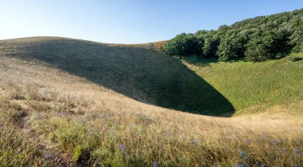 Sentiero sul Monte Subasio, tra erba dorata e un'ombra profonda che invita a scoprire cosa vedere in questo paesaggio naturale.